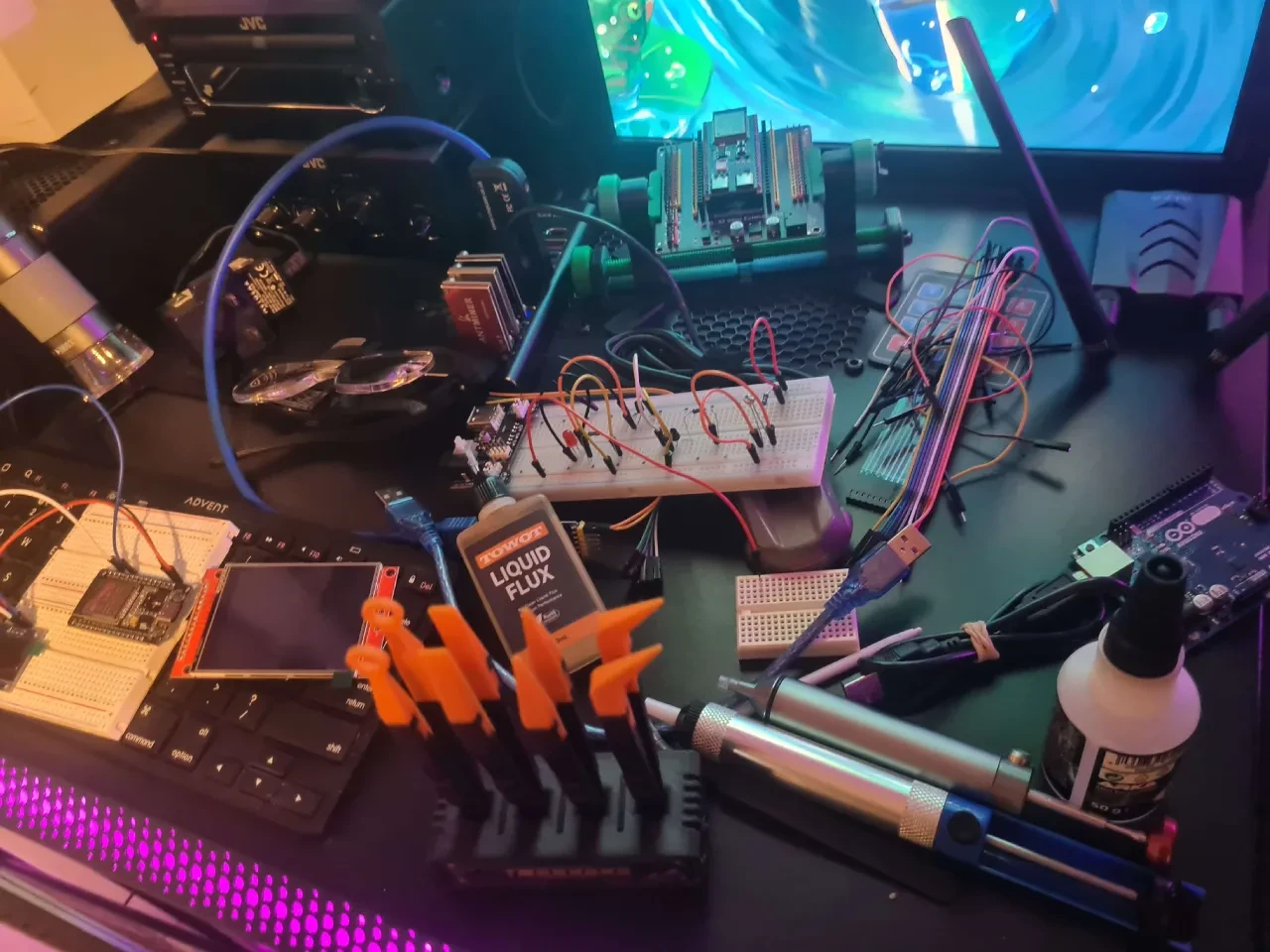 Busy electronics workbench covered with breadboards, jumper wires, tools and circuit boards