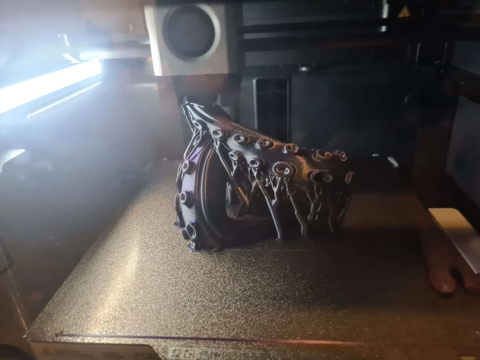 Black gothic mask taking shape on the bed of a 3D printer